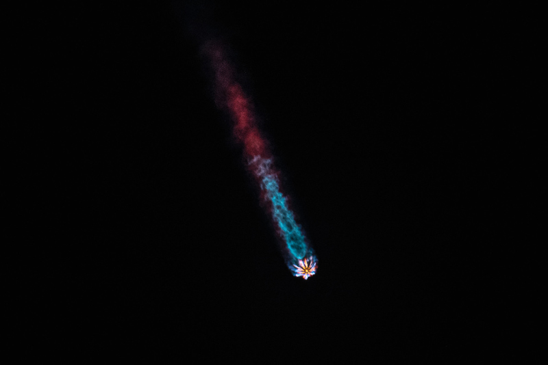 falcon 9 rocket hurdling through atmosphere with a colorful contrail