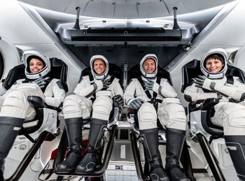 four people smiling strapped into their space seats