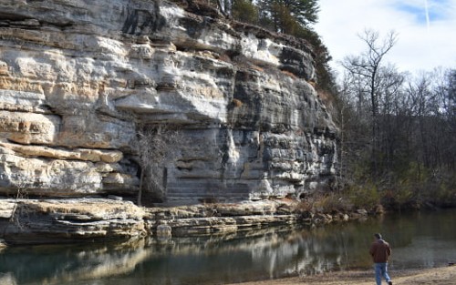 Buffalo River Trail bluffs with man walking along river.