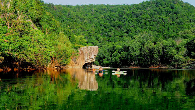 canoes floating on the river in front of a bluff
