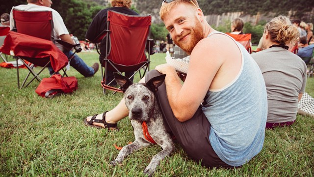 smiling young guy with his dog in the park